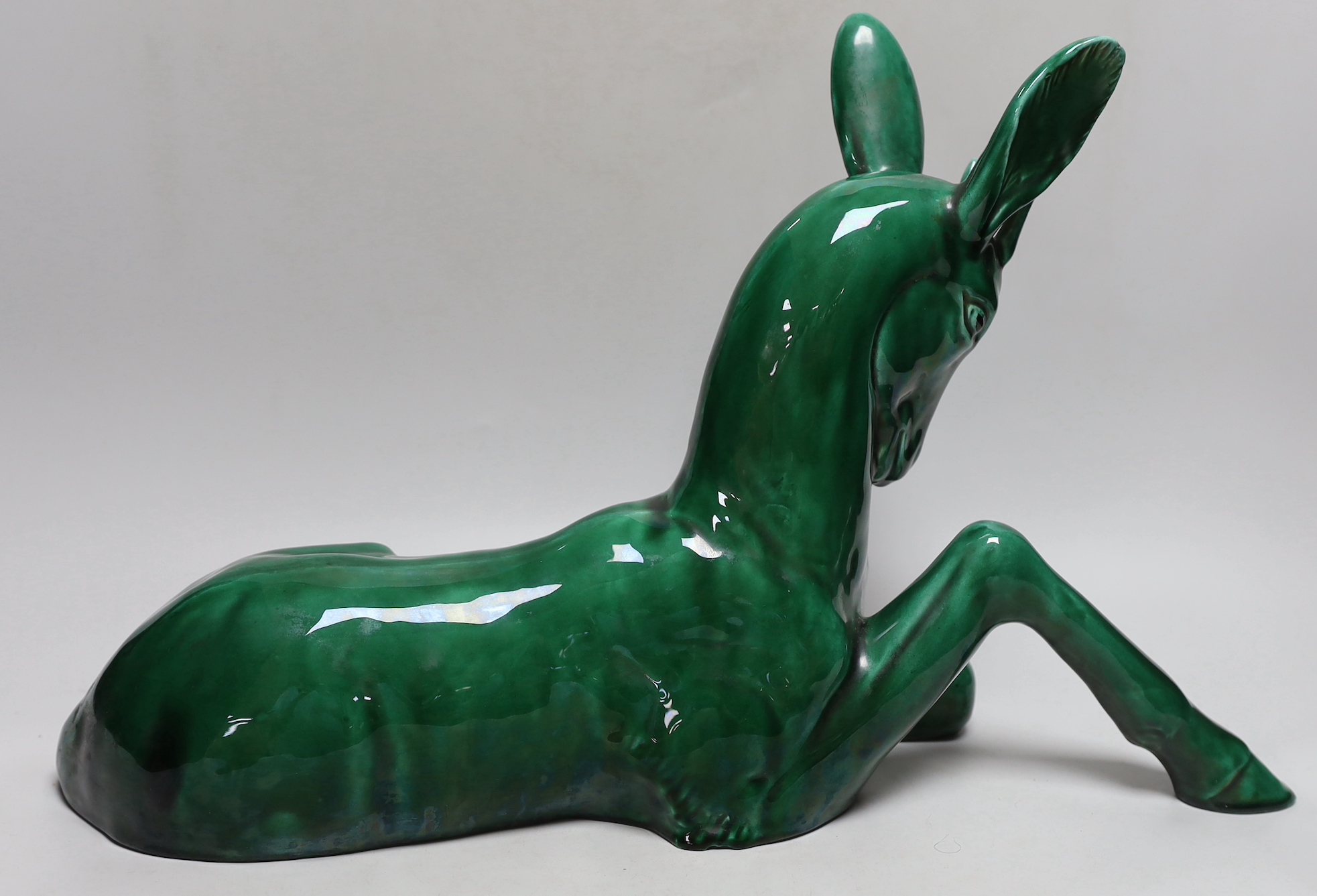 A French Art Deco large green glazed ceramic model of a seated deer, 50cm wide